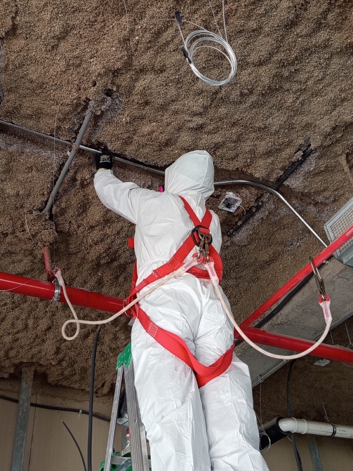 Especialista instalando canalizaciones eléctricas en cielo técnico